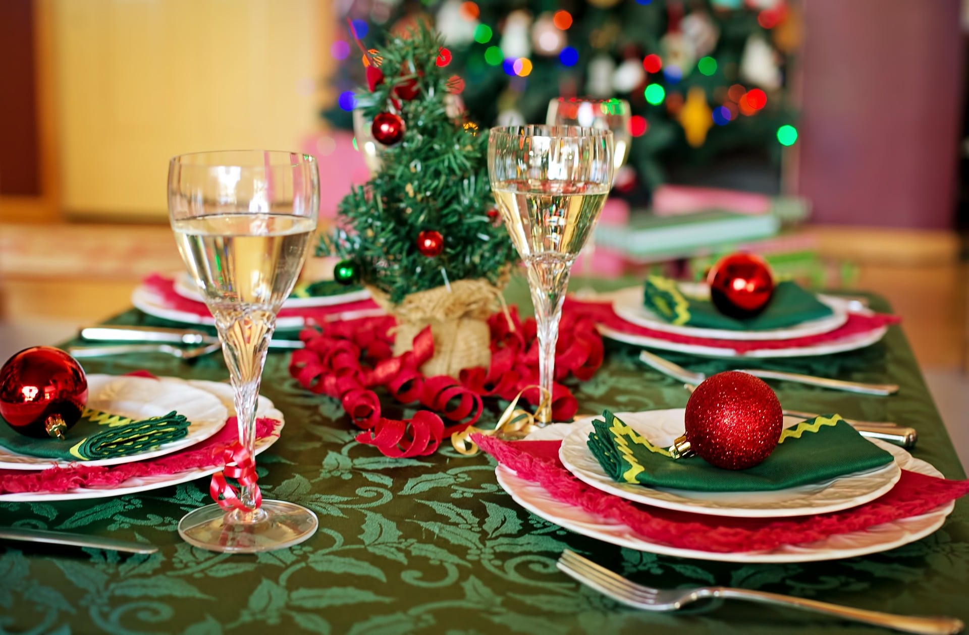 Klasična zeleno-rdeča dekoracija na jedilni mizi z dvema kozarcema penine.