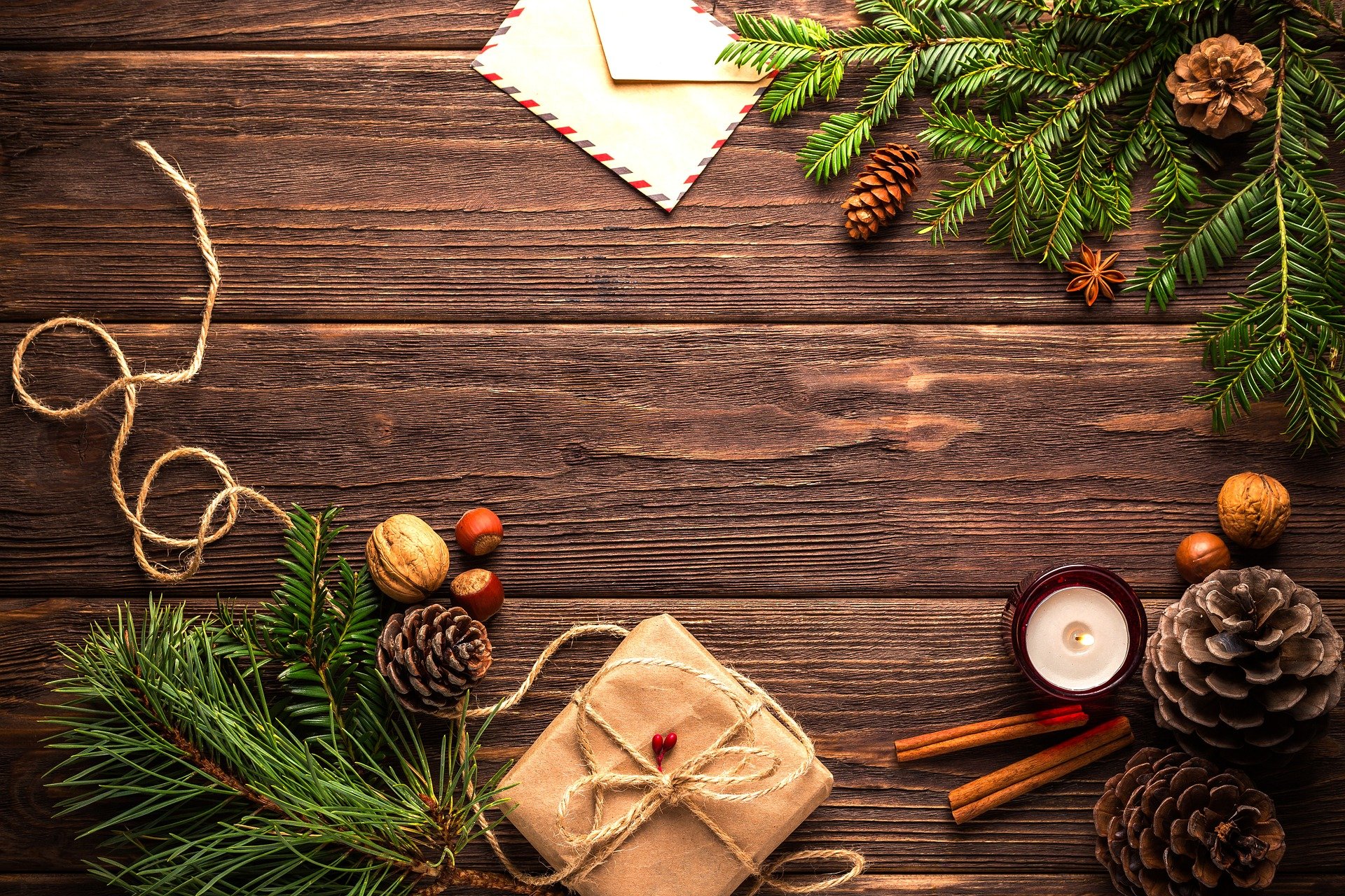 Naravni božični okraski - storži, cimet, veje smreke - na leseni mizi.