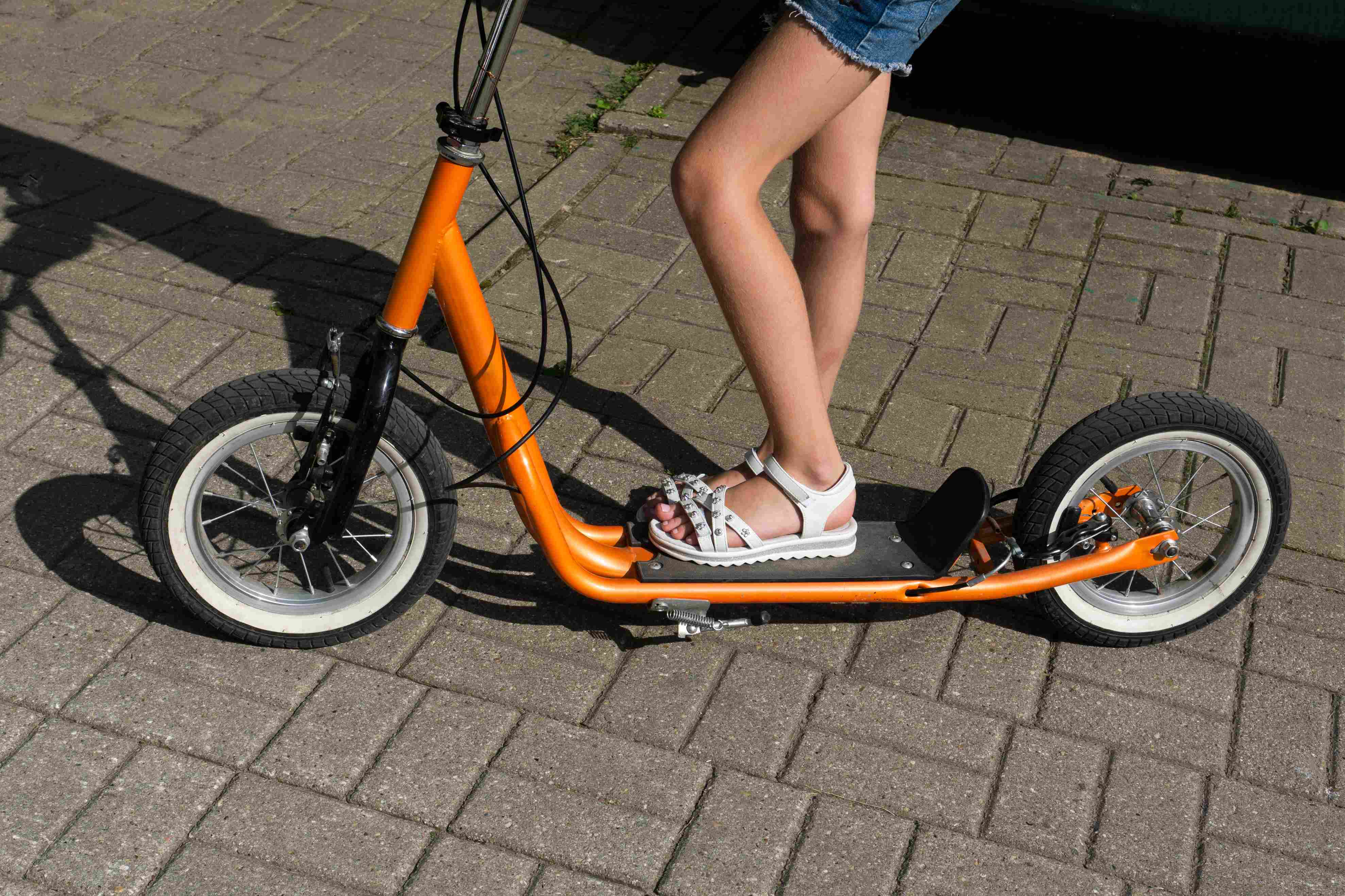 Deklica na oranžnem skiroju z napihljivimi kolesi.